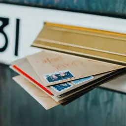 Koperty z znaczkami pocztowymi czekają na wysłanie. Dowiedz się, jak wysłać list priorytetowy, by dotarł szybko.