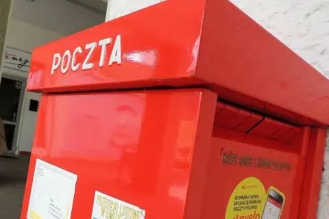 Czerwona skrzynka pocztowa z napisem "POCZTA". Warto pamiętać o poprawnym wpisaniu kodu pocztowego Toruń, aby list trafił do adresata.
