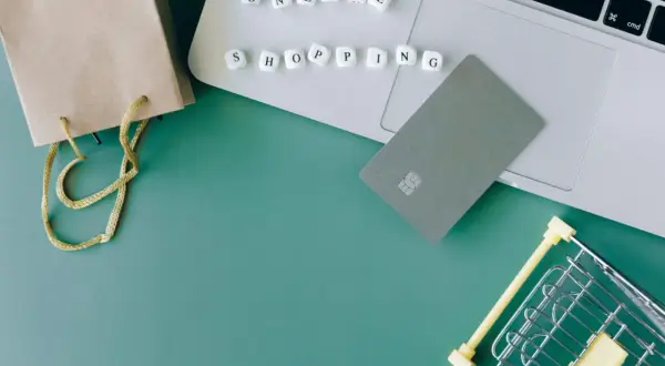 Karty płatnicze, torba i mini wózek na zakupy na laptopie symbolizują wygodne **alsendo** zakupy online.